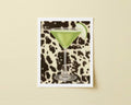 Print of green cocktail in a martini glass with an apple wedge on a black and white cow patterned background