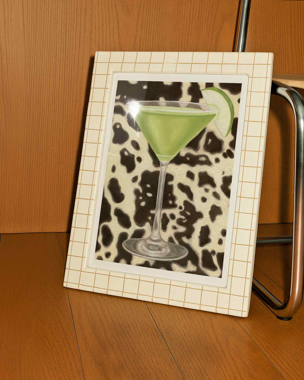 Framed picture of a green cocktail with a slice of apple on a wooden surface