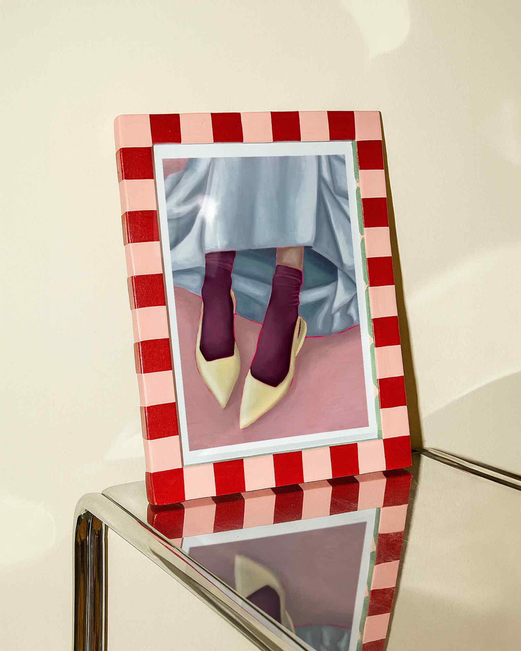 Framed art print of person wearing yellow shoes, maroon socks, and a light blue skirt on a pink background.
