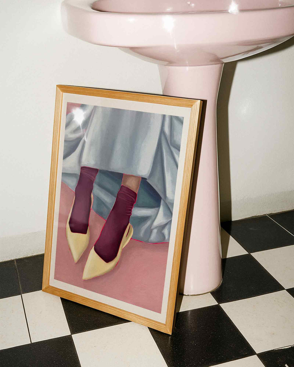 Framed art print of person wearing yellow shoes, maroon socks, and a light blue skirt on a pink background.