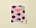 Print of a pink cocktail in a martini glass with a lime wedge on a polka dot background