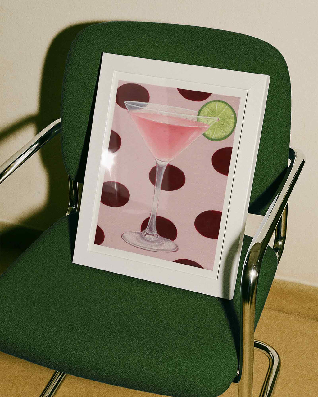 Framed picture of a pink cocktail with a lime on a green chair