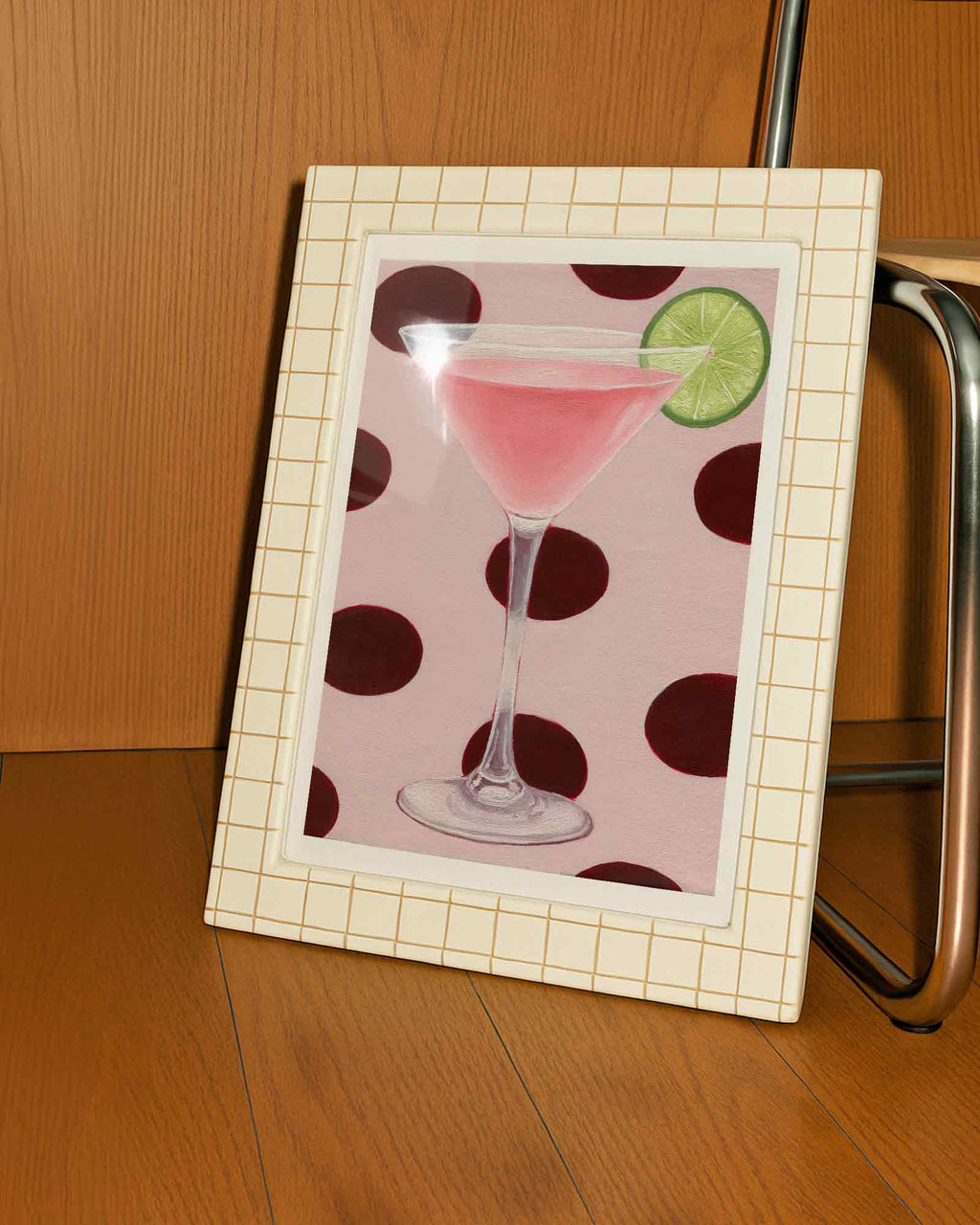Framed picture of a pink cocktail with a lime on a polka dot background