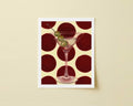 Print of a martini glass with olives on a red and beige polka dot background