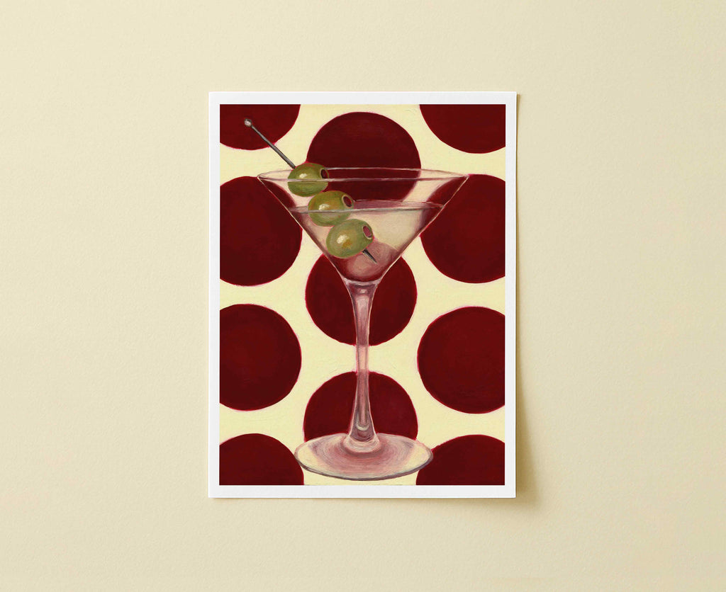 Print of a martini glass with olives on a red and beige polka dot background