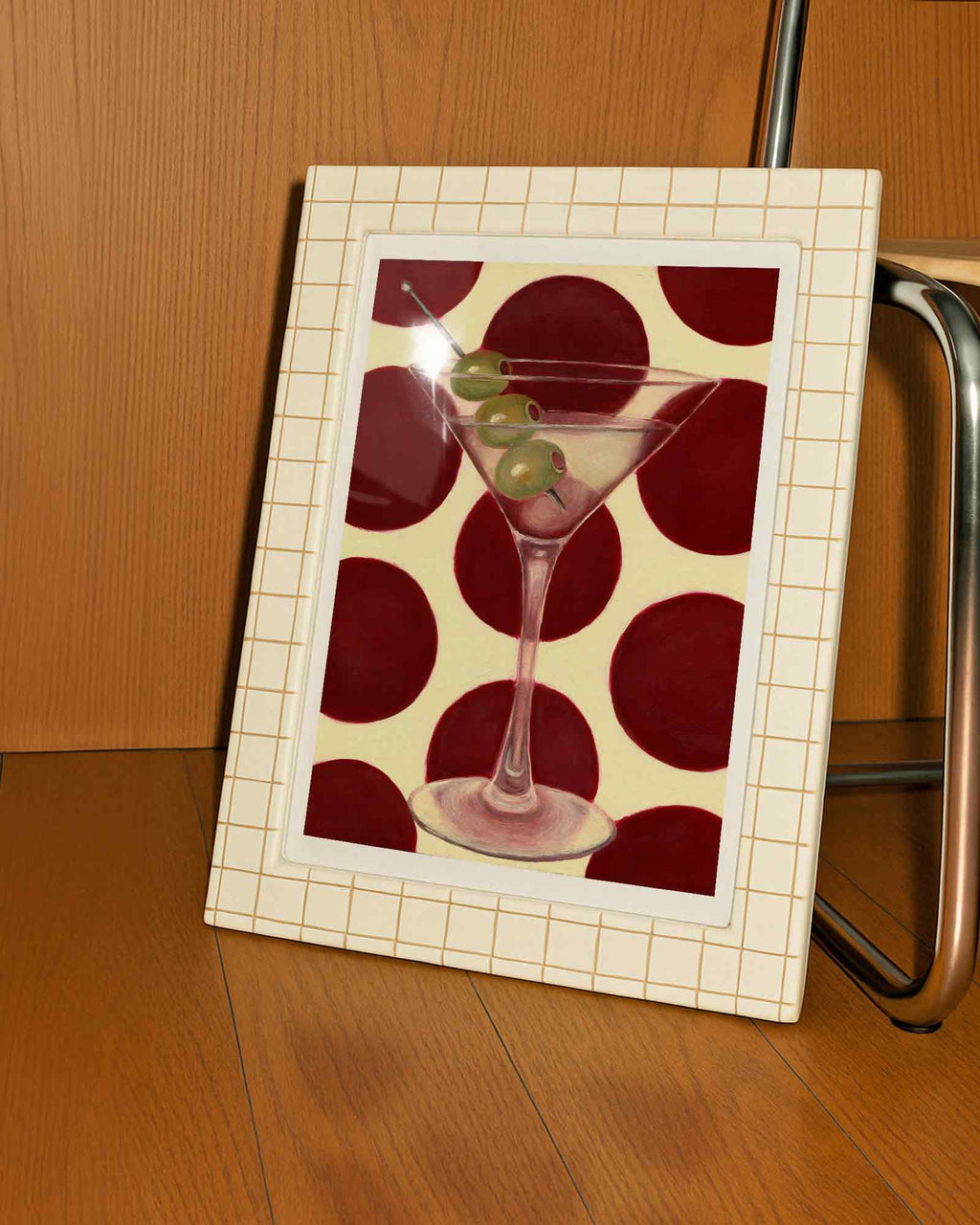 Framed artwork of a martini glass with olives on a red and beige patterned background.