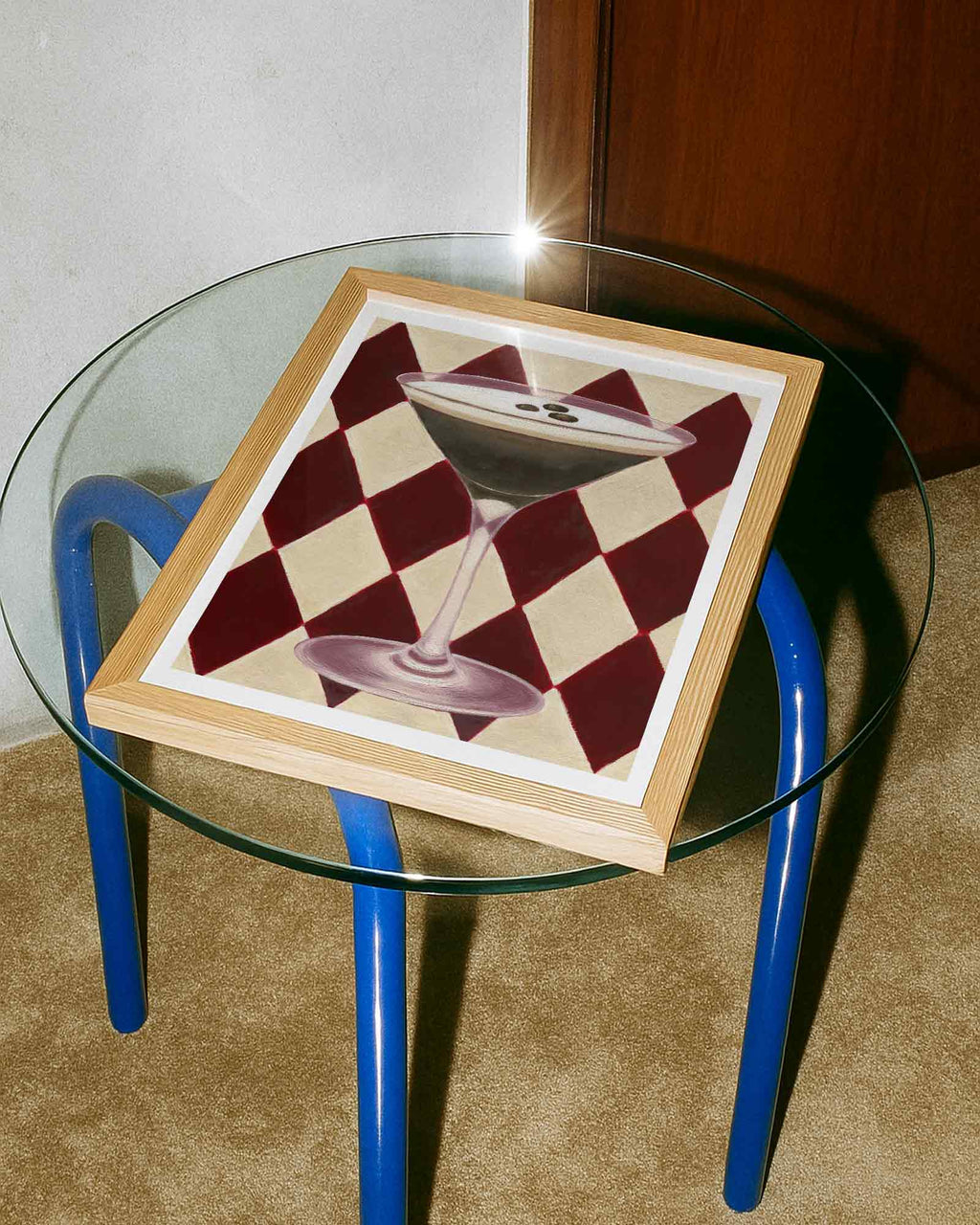 Glass table with a framed cocktail on a checkered background.