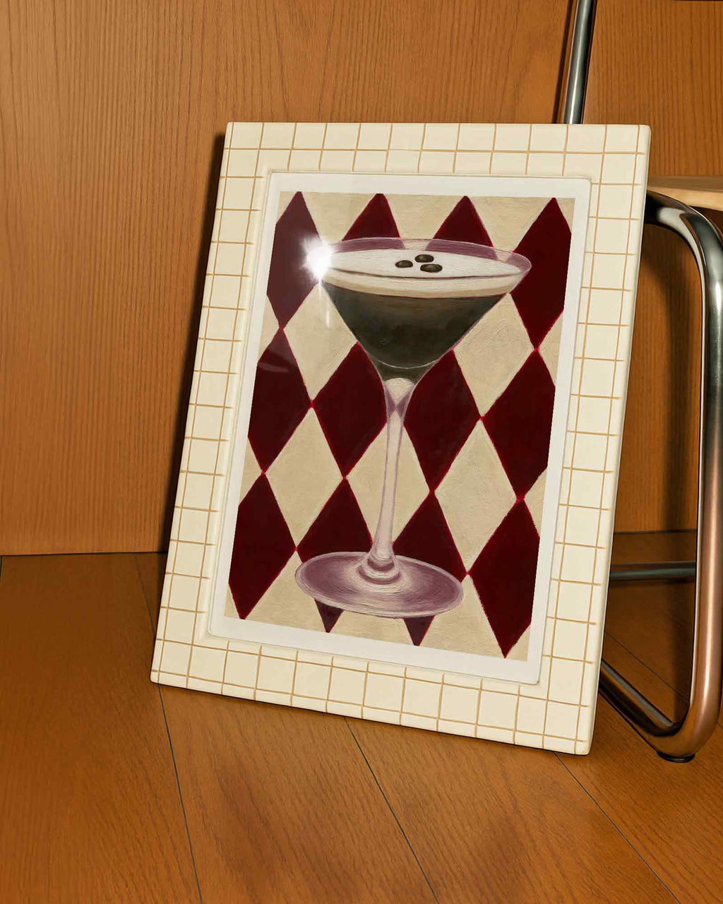 Framed artwork of a cocktail glass with checkered pattern on a wooden surface