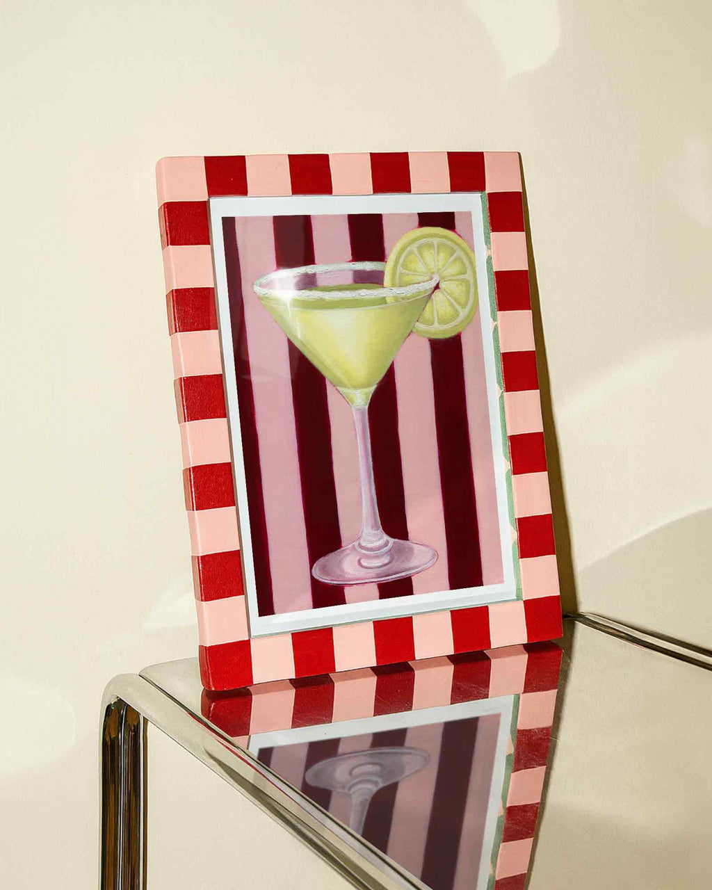 Framed artwork of a martini glass with a lemon wedge on a red and white striped background.