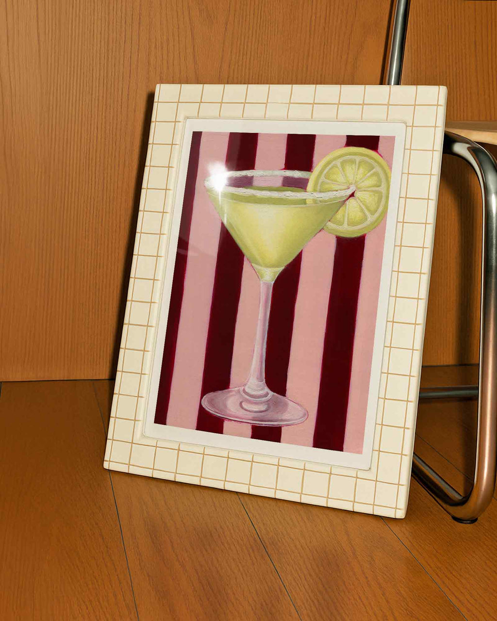 Framed artwork of a cocktail with a lemon slice on a striped background