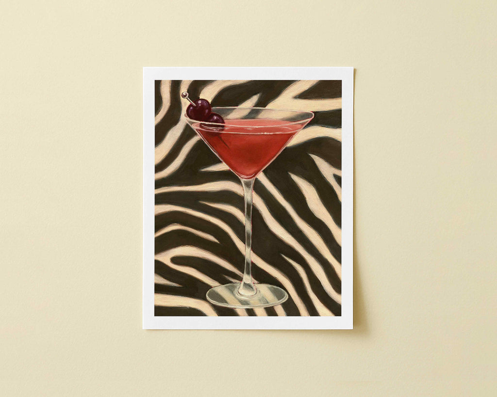 Print of orange-red cocktail in a martini glass with a cherry on a zebra-striped background