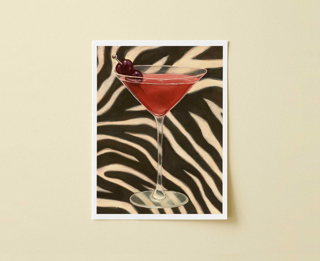Print of orange-red cocktail in a martini glass with a cherry on a zebra-striped background