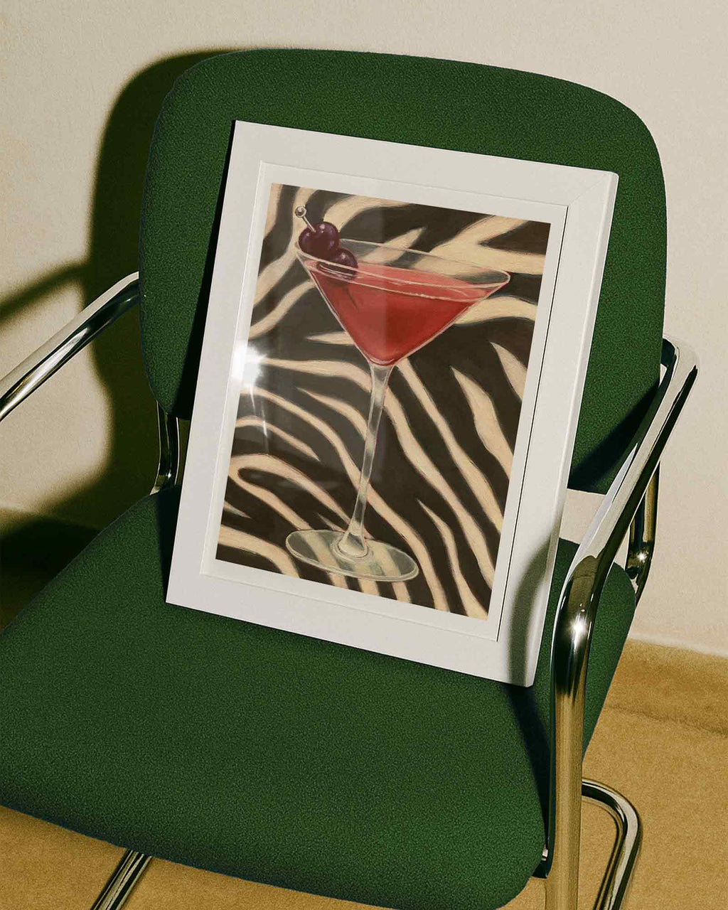 Framed picture of a cocktail with a zebra pattern on a green chair.