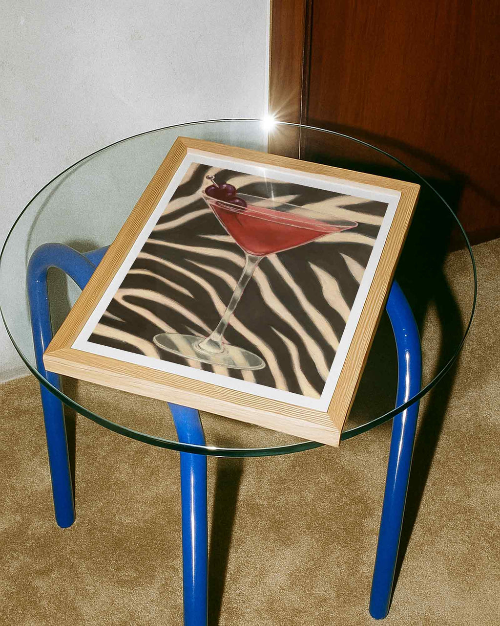 Glass table with a wooden tray featuring a zebra print and cocktail illustration.