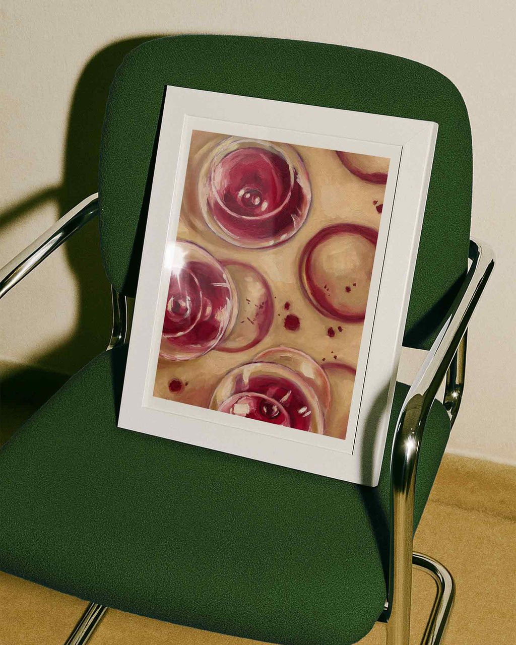 Print of red wine glasses on a beige background framed in a green chair