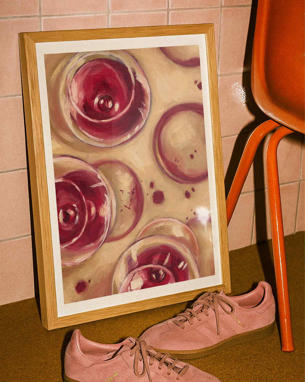 Framed artwork of wine glasses on a tiled wall next to a bottle of wine next to pink shoes