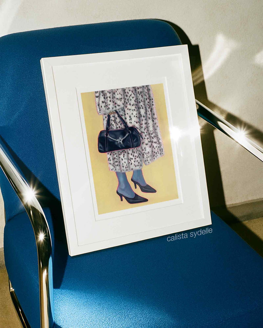 Framed artwork of a person in a fur coat and handbag placed on a blue chair.