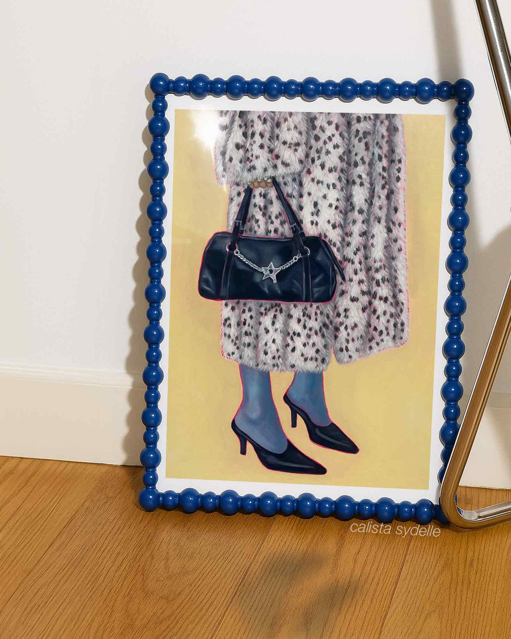 Framed artwork of a person holding a handbag with a blue frame.